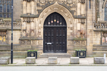 Manchester cathedral  Entrance With Ornate Archway And Planters On Quiet Urban Street