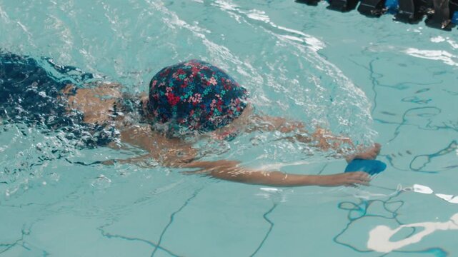 Kid learns swimming. Pre teen girl swims and learns basic skills under coach supervision in the public swimming pool