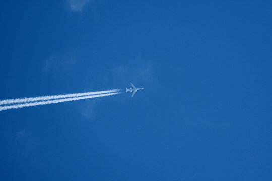 Passenger plane in flight against blue sky and clouds. Commercial airplane flying in the clear blue sky with white clouds and vapor trail. - Powered by Adobe