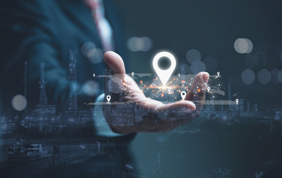 Businessman is hand holding a glowing white location pin and a digital world map. - Powered by Adobe