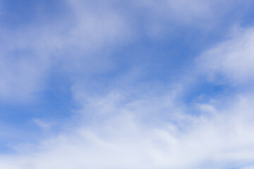 Obraz premium Soft White Clouds on a Vibrant Bright Blue Sky Background,Beautiful high-altitude cirrus clouds scattered across a clear blue sky during a bright sunny day. Perfect for use as a natural background, 