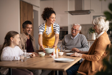 Fototapeta premium Family lunch gathering, woman serving a multi-generational meal