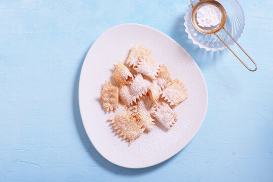 Italian carnival fritters dusted with powdered sugar. Selective focus. With free text space.