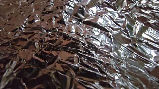 Close-up of silver crumpled foil with neutral white lighting, emphasizing the raw metallic texture and intricate folds