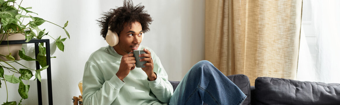 Young man enjoys a cozy moment in his modern home while sipping coffee and listening to music