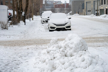 Typical winter street scene in Quebec, with abundant snow on the road, sidewalks and parked vehicles