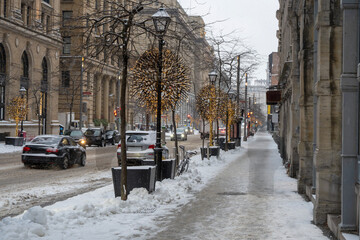 Winter traffic scene in a snowy street in Old Montreal during a snowfall covering roads and vehicles