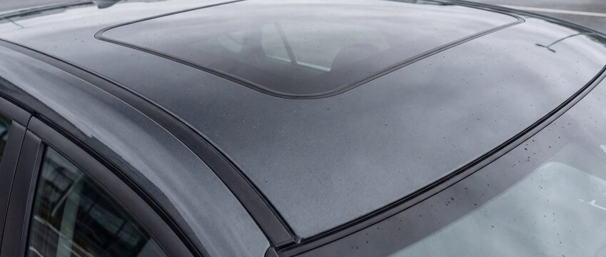 A close-up of a modern car roof with glass sunroof, showing smooth metallic paint, precision seals, and refined exterior detailing, highlighting automotive design quality and premium craftsmanship.