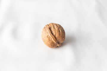 Single whole walnut lying on simple white background