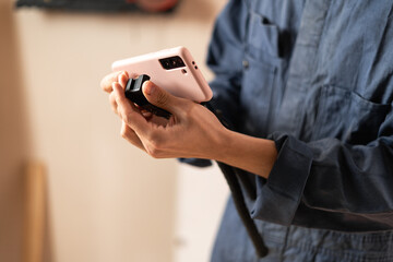 Professional handyman in workwear setting up smartphone on tripod to record video blog or streaming in workshop