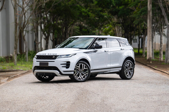 White Land Rover Range Rover Evoque front three quarter view, Premium SUV in tree lined street