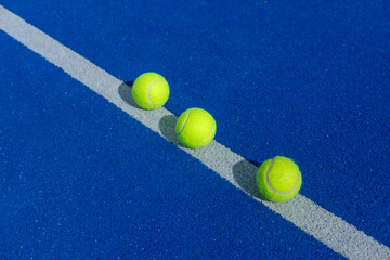 Three padel balls in a row on a blue court the concept of order and precision