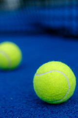 Extreme close up of a yellow padel tennis ball on a blue court