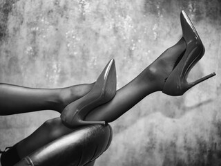 female legs in black stockings and stiletto heels against a wall