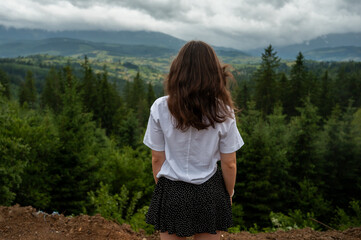 Female traveler enjoying scenic foggy landscape and evergreen forest in summer