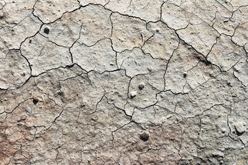 Cracked dry soil texture background. Parched earth surface with deep fissures. Natural drought land pattern. Rough arid ground detail. Brown gray clay terrain closeup. Dry climate concept backdrop.