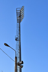 A stadium floodlight mast against a blue sky
