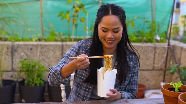 Young east asian woman eating instant noodles outdoor - Thai food, lifestyle and young people concept