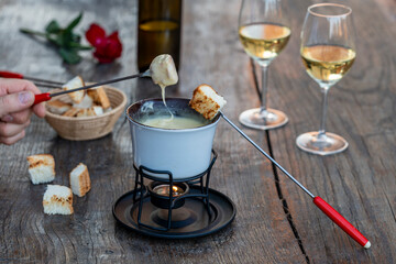Fondue with tasty melted cheese, forks, breads and wine on wooden table, closeup