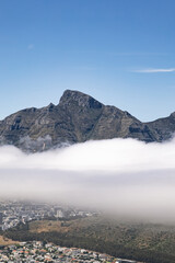 City landscape with mountain peak towering above a thick layer of white cloud. Nature and urban scene with dramatic weather for travel and tourism concept.