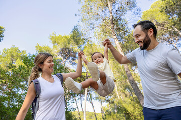 Naklejka premium Happy toddler playing with parents during forest walk