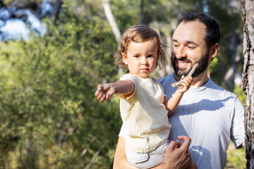 Obraz premium Little girl holding a stone while being carried by her father in the forest