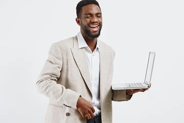 Fotobehang Diamanten Smiling man wearing beige blazer and white shirt holding open laptop computer in hand, looking friendly, confident, and professional isolated on plain white background, studio portrait with modern  © SHOTPRIME STUDIO