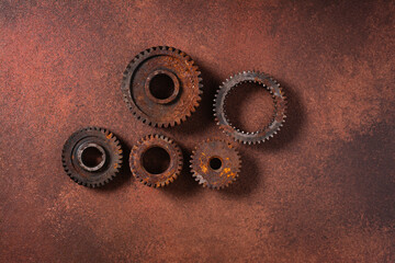several old rusty gears from a car gearbox on a brown background