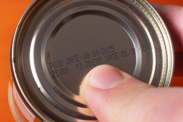 A man checks the expiration date and production date on a metal can.