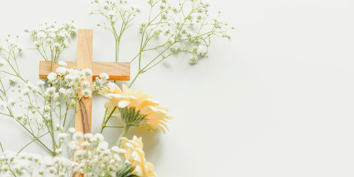 Christian Cross with White Gypsophila and Yellow Gerbera Flowers on Light Blue Background With Copy Space. Concept of Easter Celebration, Palm Sunday, Religious Holidays, Grace and Spring Renewal
