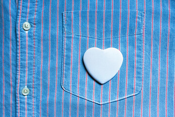 Heart badge mockup. White pin shape. Striped blue shirt. Denim pocket background. Love symbol button. Blank accessory template. Textile fabric texture. Romantic merchandise item. Close up clothing