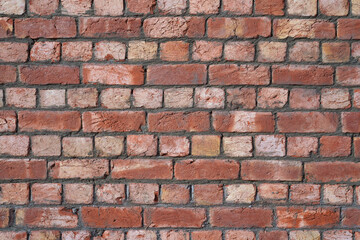 Obraz premium Brick wall. Industrial textured background. Red hand-molded bricks, with visible layers of clay and a rough texture, freshly laid in cement mortar. Careful masonry of uneven bricks.