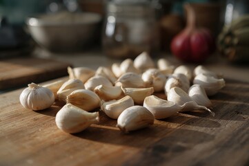 Whole and peeled garlic cloves on wooden cutting board in natural daylight