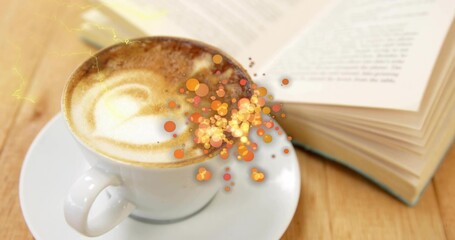 Showing white ceramic cup and saucer with latte art on wooden table, paperback, spoon, orange bokeh