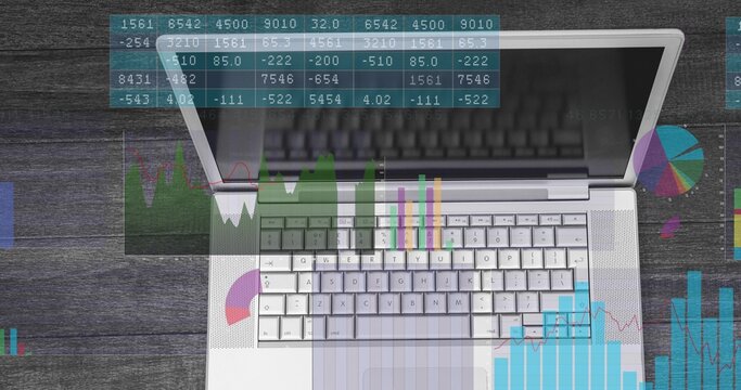 Displaying silver laptop showing keyboard and trackpad at office desk, with overlaid data charts - Powered by Adobe