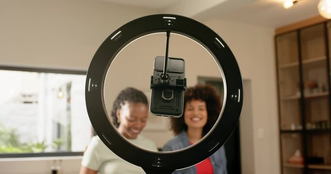Upon recording, Diverse female friends focusing at countertop under ringlight filming tutorial