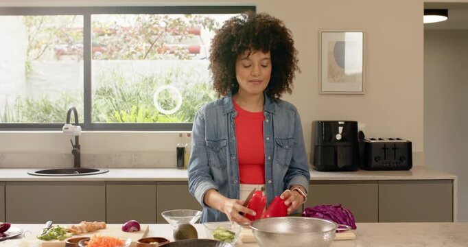 Lifting red pepper halves into mixing bowl, Diverse female friends prepping salad on kitchen island