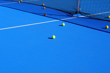 Tennis concept. Yellow and orange balls scattered on a blue tennis court.
