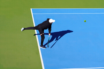 Tennis concept. Aerial view. Minimalist faceless image of a tennis player playing on a blue court.