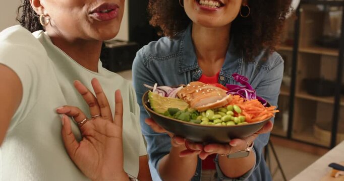 Extending poke salad bowl to camera, Diverse female cohosts sharing recipe commentary in kitchen