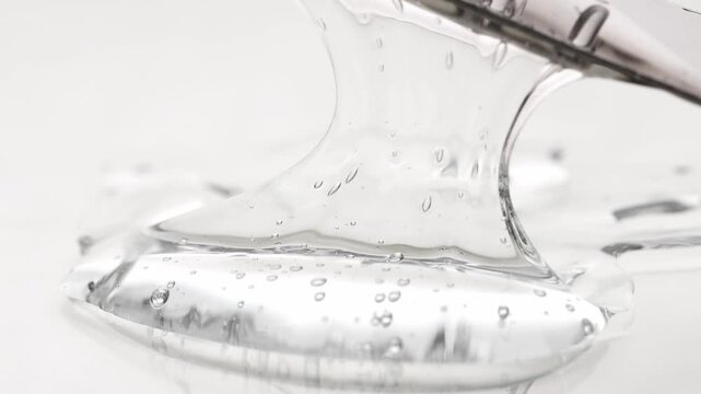 Transparent gel texture with bubbles stretches and drips from the tool, close-up.
