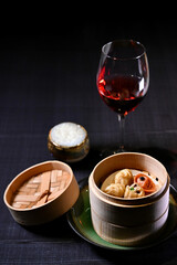Dim Sum are chinese dumplings served in a bamboo basket and Italian red wine