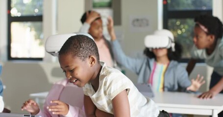 African American children leaning over tablet, helping student in VR headset in class, copy space - Powered by Adobe