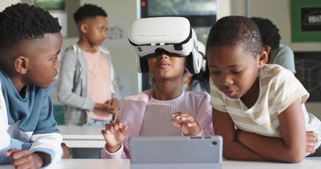 African students watching youth girl donning and using white VR headset with tablet for class demo