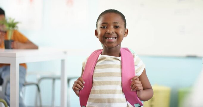 African female child standing at class front holding pink backpack straps smiling reacting to cue