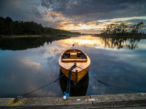 Sch&ouml;nes Holzboot am Steg bei Sonnenuntergang in S&uuml;dschweden