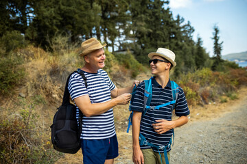 Father adjusts his son&rsquo;s backpack during a summer hike. Caring parenting, guidance, and family support in nature, ideal for outdoor, travel, and lifestyle concepts.