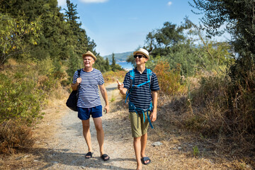 Father and son hiking together during summer. Family bonding, guidance, and support in nature, ideal for outdoor lifestyle, travel, and parenting concepts.