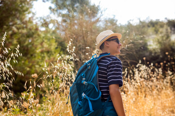 Teenage boy hiking in summer with a backpack. Outdoor adventure, active lifestyle, and exploration in nature, perfect for travel and summer leisure concepts.