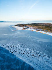 Ice Floes and Frozen Surface in Foreground with Forested Land near Lanken at Sunset